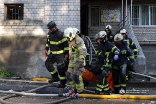Rescuers carry a body of the person found under debris of a building which was hit during Russian drone strike, amid Russia's attack on Ukraine, in Dnipro